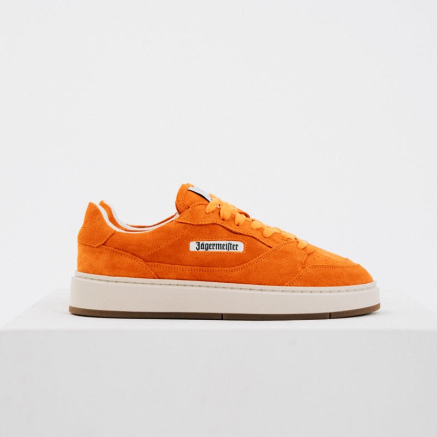 Jägermeister x Flowers For Society The Curt Sneaker i orange mocka, sidovy mot vit bakgrund med Jägermeister-logga på sidan