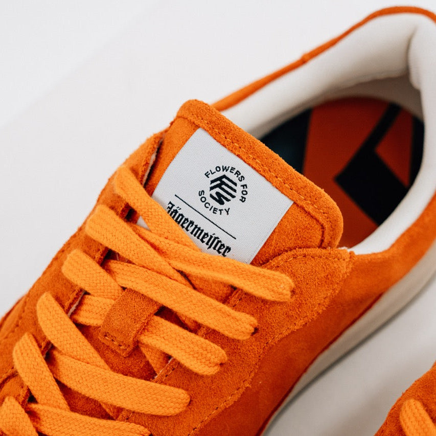 Jägermeister x Flowers For Society The Curt Sneaker i orange mocka, närbild på tungans kollaborationsetikett